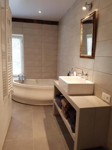 La salle de bains blanche est pourvue d'un lavabo et d'une baignoire. dans l'établissement Ecrainville, charming house near Etretat, à Écrainville
