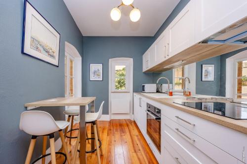 une cuisine avec des murs bleus et des armoires blanches dans l'établissement Maison Lou Blau, à Albi