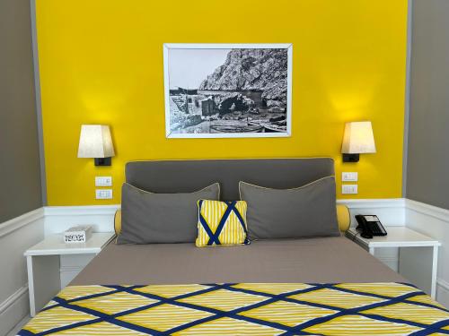 a bedroom with a bed with a yellow wall at Hotel Della Piccola Marina in Capri