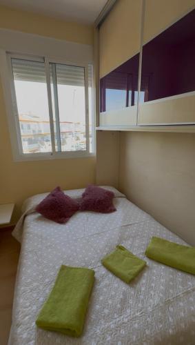 a bedroom with a bed with green and purple pillows on it at Apartamento confortable en Mazagón in Mazagón