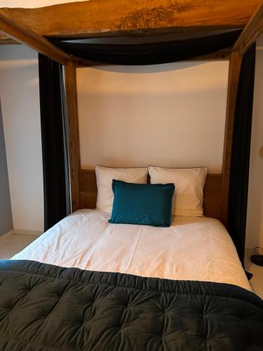 Una cama con una almohada azul encima. en Kimy Villa Lunoterie Futuroscope Piscine et Spa, en Oyré