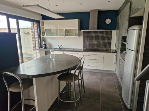 une cuisine avec des armoires blanches et un comptoir noir dans l'établissement La maison des Ifs, à Tourville-les-Ifs