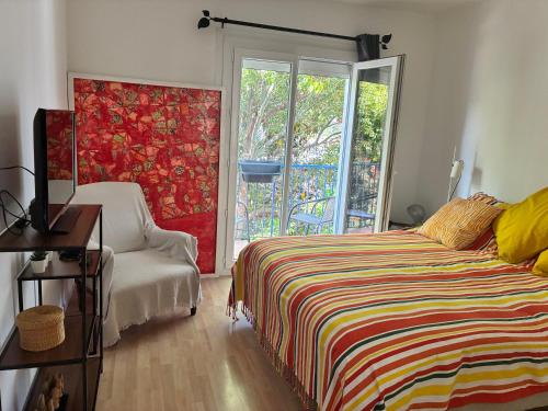 a bedroom with a bed and a chair and a window at villa de canet 66 in Canet-en-Roussillon