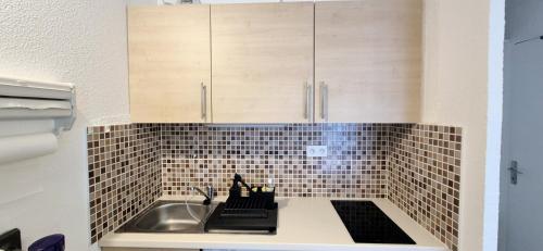 Il dispose d'une cuisine avec un évier et un mur carrelé. dans l'établissement Studio cv 4p, parking privée cosy design, à La Grande Motte