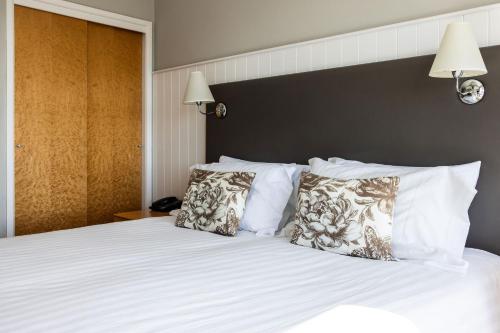 a bedroom with a bed with white sheets and pillows at Hotel Cristina in St Lawrence