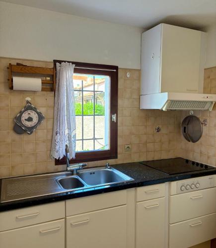 une cuisine avec un évier et une fenêtre dans l'établissement Maison mitoyenne résidence Piscine proche plage 5PB157, au Barcarès