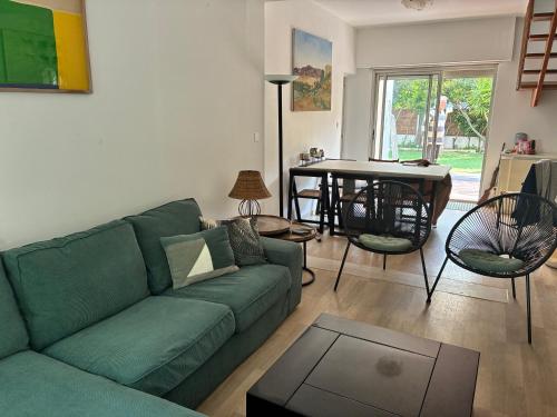 a living room with a green couch and a table at villa de canet 66 in Canet-en-Roussillon