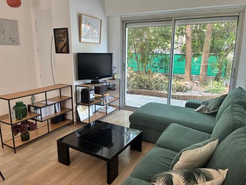 - un salon avec un canapé vert et une télévision dans l'établissement villa de canet 66, à Canet