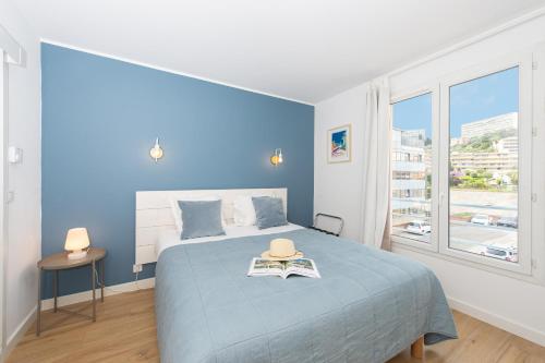 - une chambre bleue avec un lit doté d'un chapeau dans l'établissement Jardin du cap, à Roquebrune-Cap-Martin