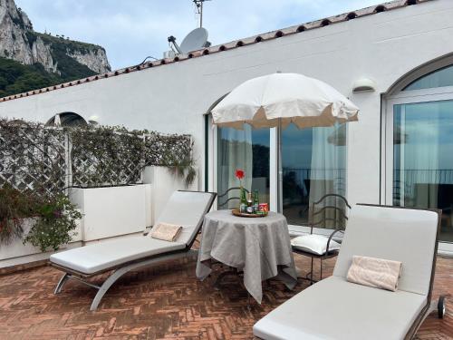 a patio with two chairs and a table with an umbrella at Hotel Della Piccola Marina in Capri