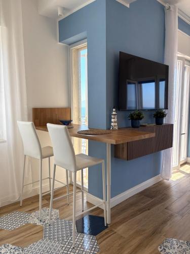 a dining room with a table and a tv on a blue wall at L'Abbraccio di Parthenope in Torre del Greco