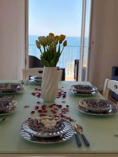 a table with plates and a vase with flowers on it at L'Abbraccio di Parthenope in Torre del Greco