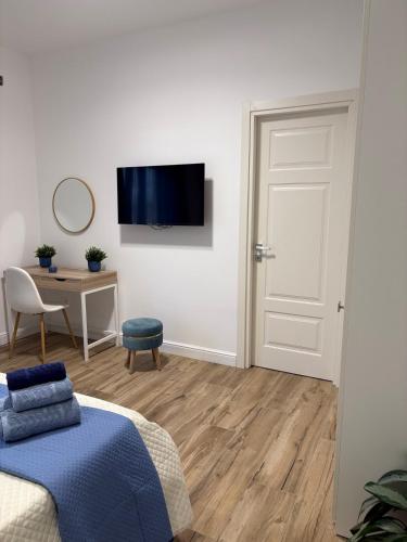 a bedroom with a bed and a desk and a television at L'Abbraccio di Parthenope in Torre del Greco