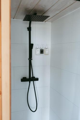 - une douche dans une chambre blanche avec un tuyau noir dans l'établissement La cabane a fleur d eau au cœur de la Camargue, à Saint-Gilles