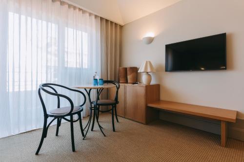 a hotel room with a table and chairs and a television at Torel Saboaria in Porto