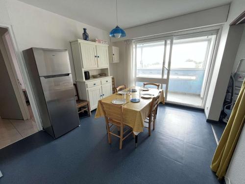 une cuisine avec une table avec des chaises et un réfrigérateur dans l'établissement Spacieux T3 idéalement situé près de la plage et des commerces, parking privatif inclus - FR-1-324A-2, à Saint-Hilaire-de-Riez