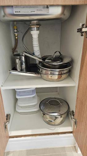 a kitchen cabinet with some pans and dishes in it at Comfort and Practicality Campinas in Campinas