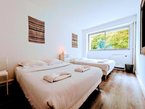 two beds in a room with a window at Comfortable appart near Paris in Colombes
