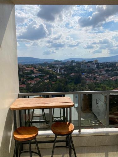 a table and two stools on a balcony with a view at TWIGER HOUSE by WILSON in Kigali