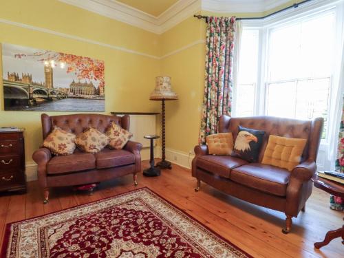a living room with two leather couches and a rug at Mullans in Southport
