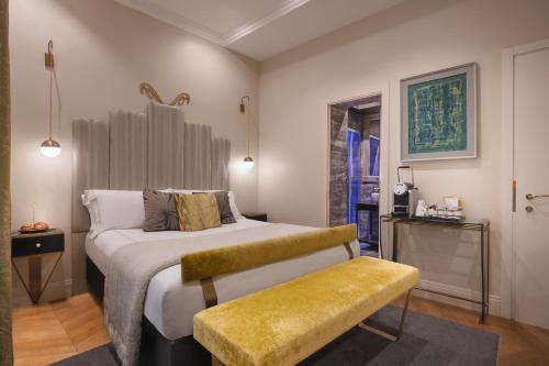 a bedroom with a large bed with a yellow bench at Torre Argentina Relais - Residenze di Charme in Rome