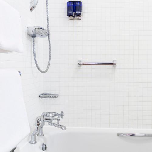 a white tiled bathroom with a shower and a sink at Hotel Cristina in St Lawrence