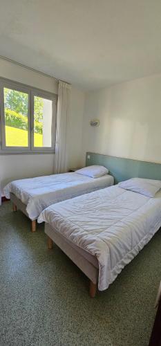 two beds in a room with two windows at Pause nature à Souraïde au cœur du pays Basque in Souraïde