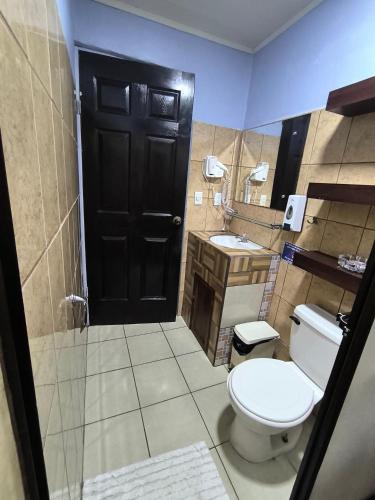 a bathroom with a toilet and a sink and a black door at La Martha in Sarapiquí
