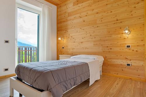 Un dormitorio con una cama y una pared de madera. en Agritur Montibeller Fravort, en Marter di Roncegno
