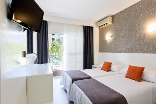 duas camas num quarto de hotel com uma televisão de ecrã plano em Hotel Don Miguel Playa em Playa de Palma