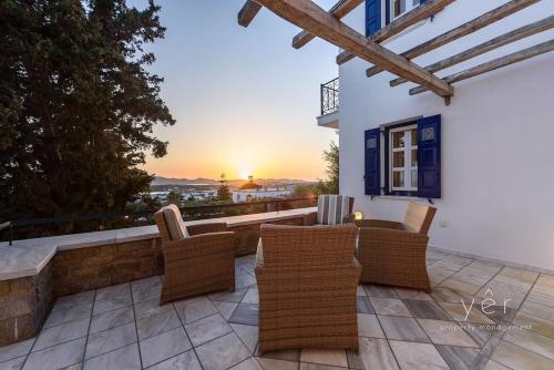 a patio with chairs and a sunset in the background at 6BR Villa with Private Pool, 4 Baths & Garden -PADMA in Angairiá