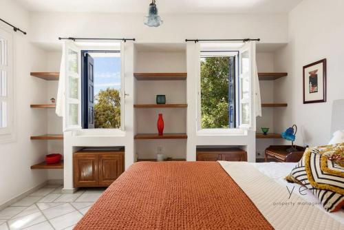 a bedroom with two windows and a bed with an orange blanket at 6BR Villa with Private Pool, 4 Baths & Garden -PADMA in Angairiá