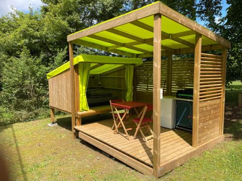un gazebo en bois avec une chaise rouge à l'intérieur dans l'établissement Camping le Convivial Cop'Camp 2 personnes, à Saint-Martial-de-Nabirat