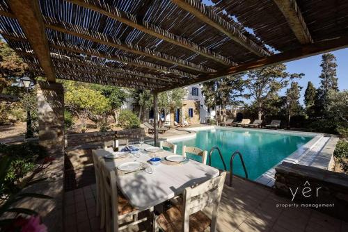 a patio with a table and a swimming pool at 6BR Villa with Private Pool, 4 Baths & Garden -PADMA in Angairiá