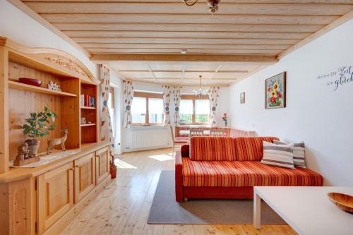 a living room with a red couch and a table at Ferienhaus Hirschalmblick in Söll