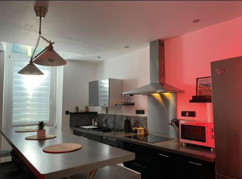 a kitchen with a counter and a red wall at Appart Idéalement situé et proche du théatre antique in Orange