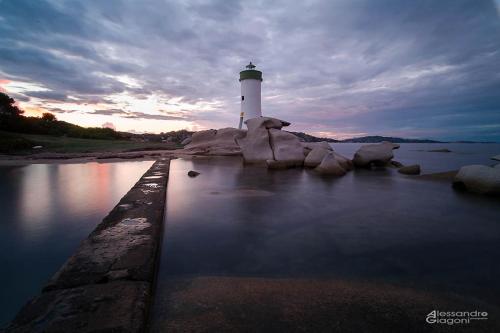 a lighthouse on the shore of a body of water at Residenze L'Isola Surf House in Porto Pollo