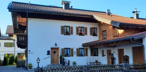 a white house with a wooden roof and a fence at Gästehaus Annemarie in Reit im Winkl