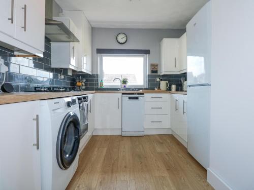 a kitchen with white cabinets and a washer and dryer at Hendre in Abergele