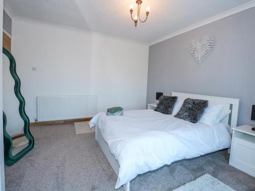 a white bedroom with a white bed and a chandelier at Hendre in Abergele