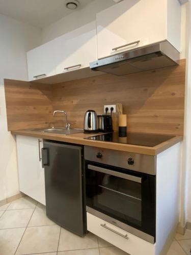 une cuisine avec un évier et une cuisinière dans l'établissement Petite maison indépendante à 7mn de la plage, à Douvres-la-Délivrande