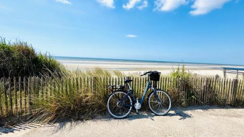 a bike parked on a beach next to a fence at Nouvel Vague - Appartement au pied de la mer Merlimont Plage in Merlimont