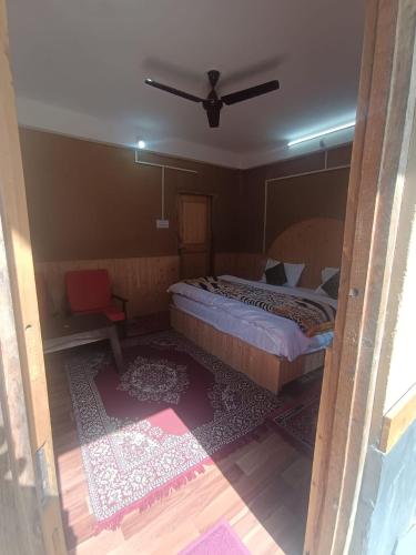 a bedroom with a bed and a ceiling fan at Tirthan Hill Wander Stay in Banjār