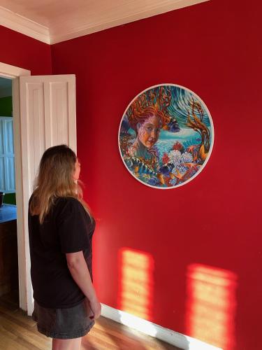 a woman looking at a painting on a red wall at Hostal Kuyen in Pichilemu