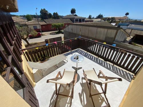 a patio with two chairs and a table on a balcony at Hostal Kuyen in Pichilemu