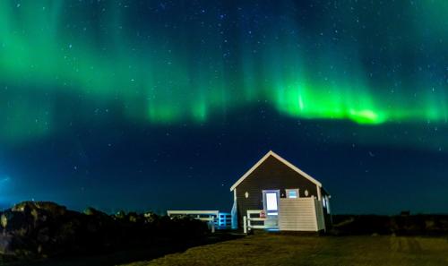 a cabin under the northern lights in the sky at Garður Apartments in Gardur