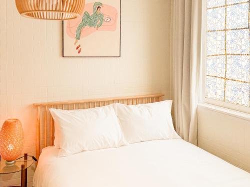 a bedroom with a bed with white sheets and a window at Won stay in Osan