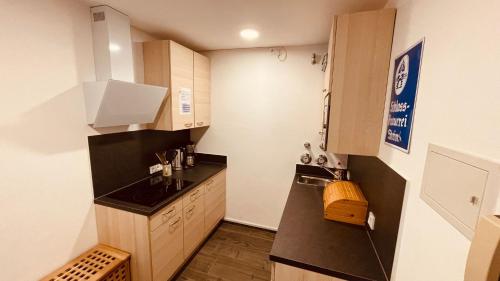 a small kitchen with a black counter top and cabinets at ciao-aschau Gschwendtnerhof Ap21 Kappes in Aschau