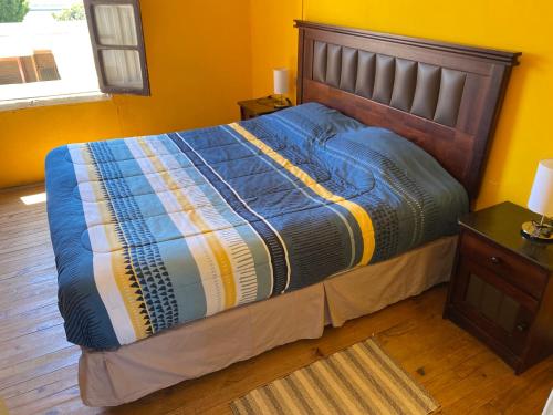 a bed with a blue comforter in a bedroom at Hostal Kuyen in Pichilemu