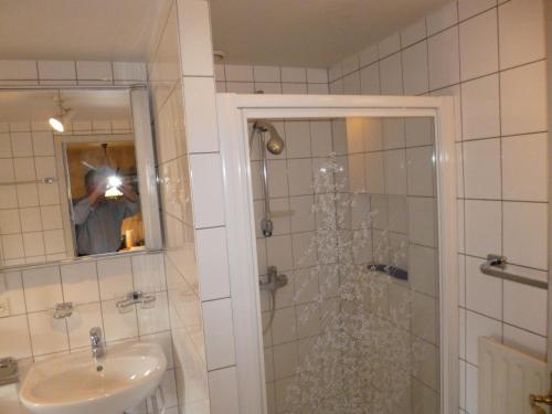 un homme prenant une photo d'une salle de bains avec douche dans l'établissement Roaringtwenties, à La Celle-sous-Gouzon